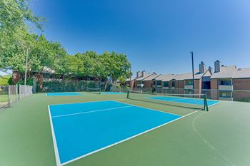 A tennis court with a blue surface and a green fence.